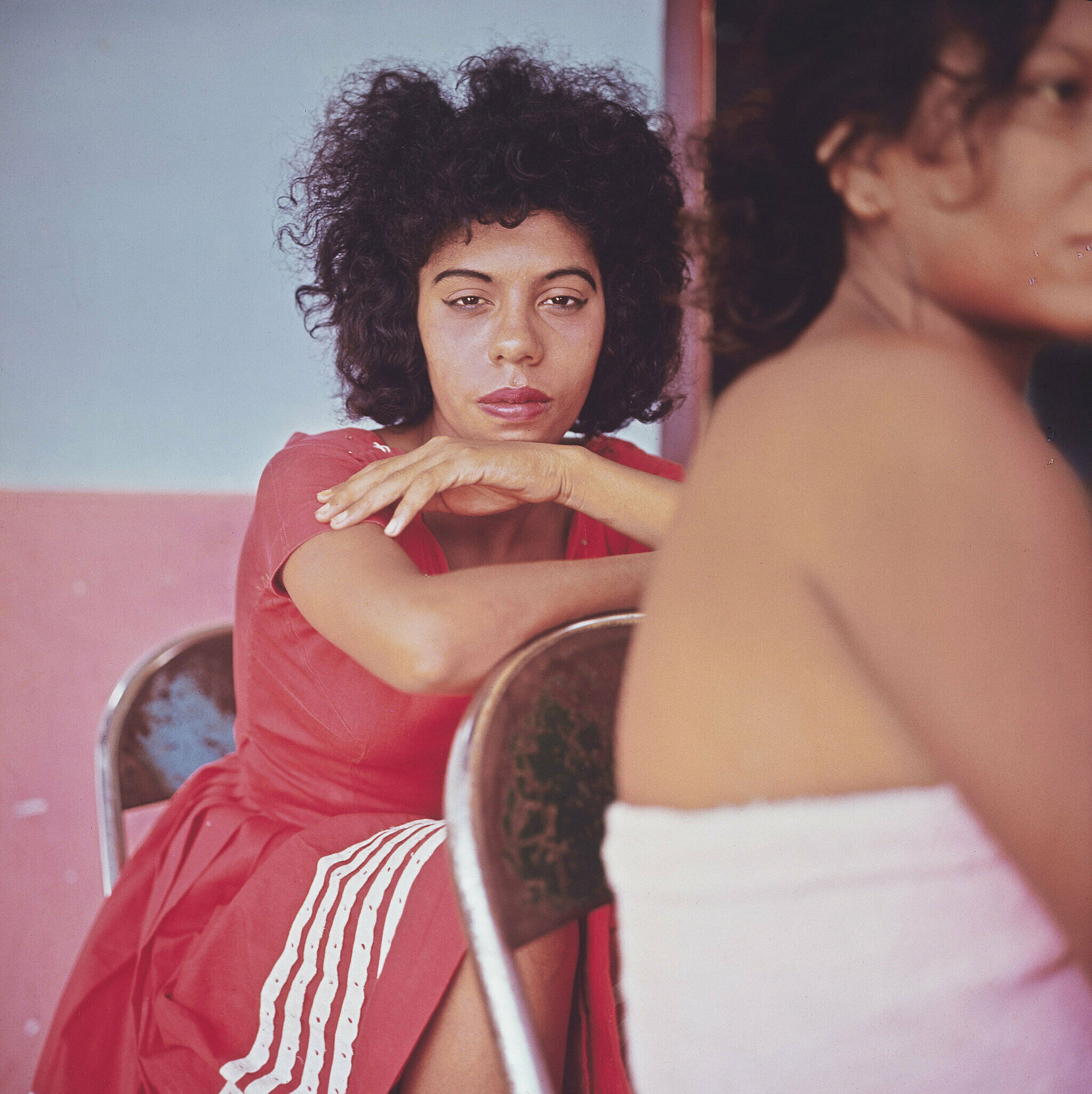 A woman in a red dress looking directly at the camera.